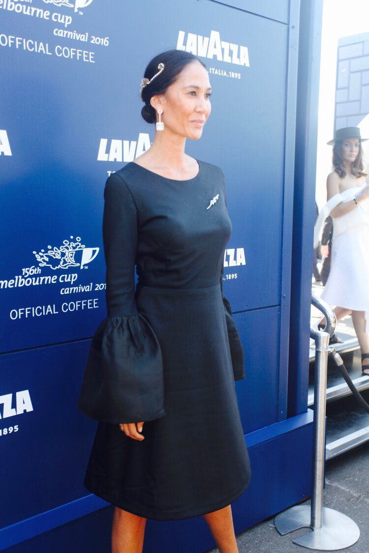 A woman in a black dress is standing in front of a lavazza sign