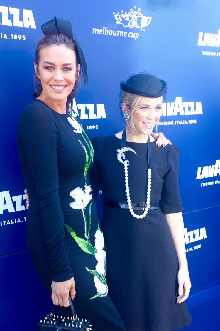 Two women standing next to each other in front of a lavazza sign