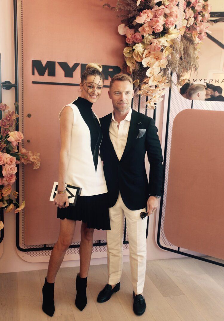 A man and a woman are posing for a picture in front of a sign that says myr