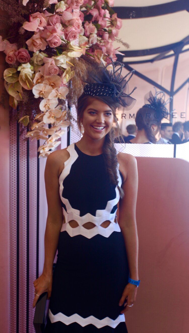 The woman is wearing a black and white dress and a hat.