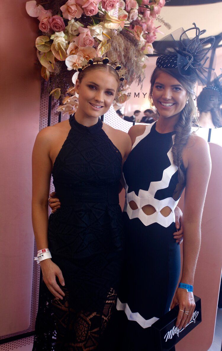 Two women in black and white dresses are posing for a picture.
