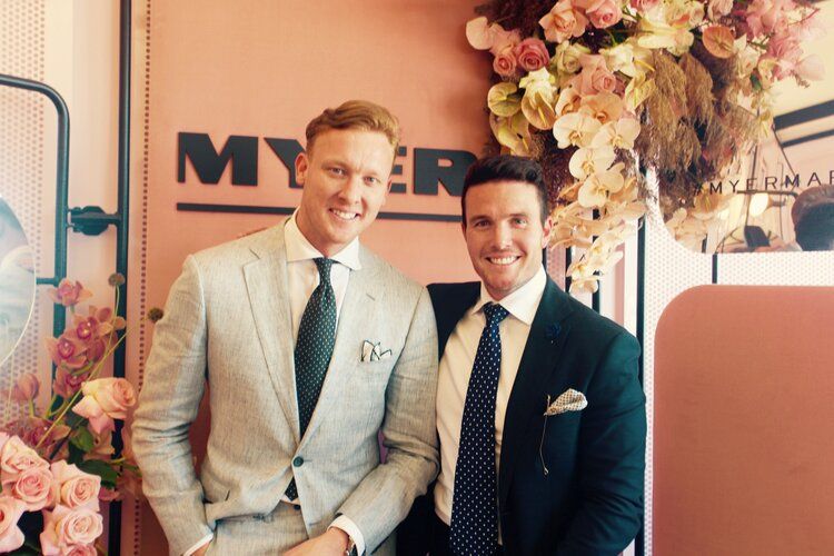 Two men in suits and ties are posing for a picture.