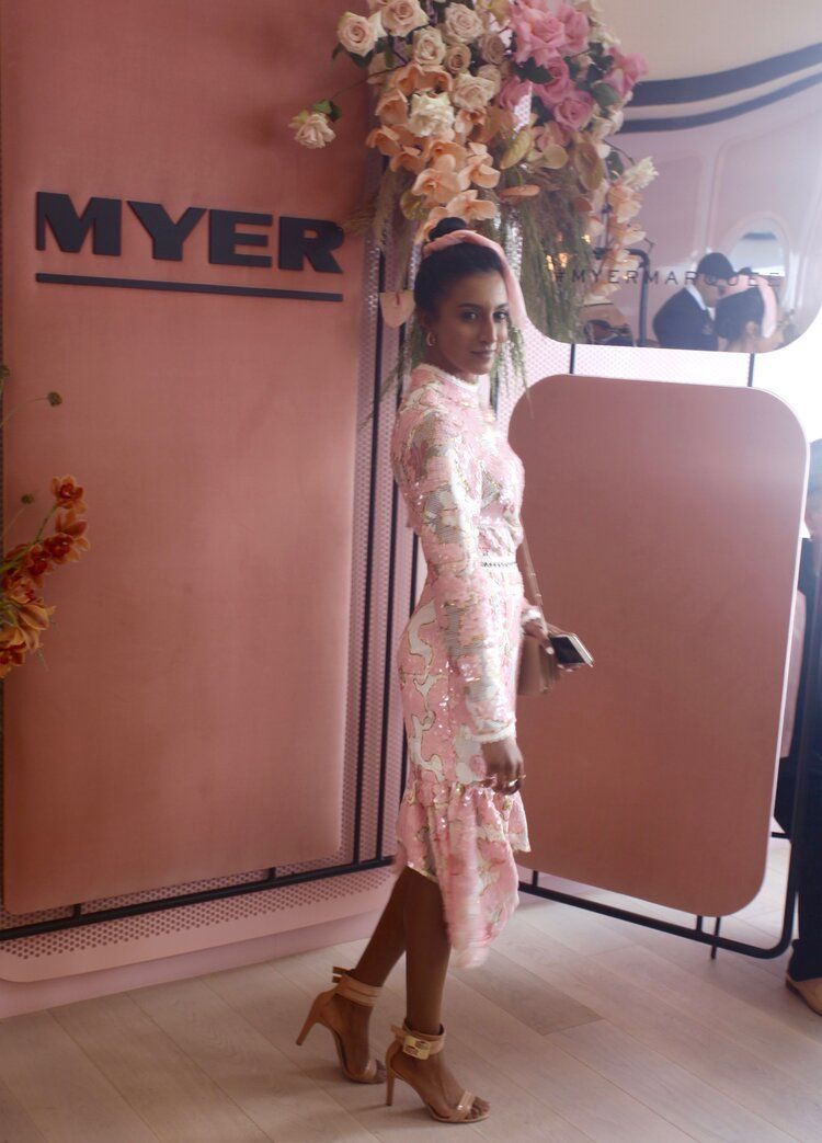 A woman in a pink dress is standing in front of a myer sign