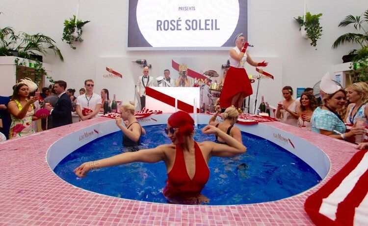 A woman in a red swimsuit is swimming in a pool surrounded by people.
