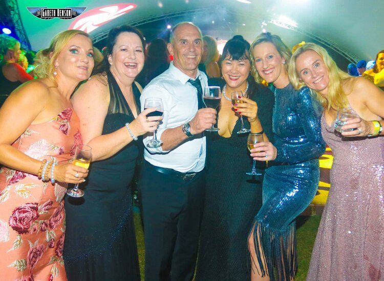 A group of people standing next to each other holding wine glasses