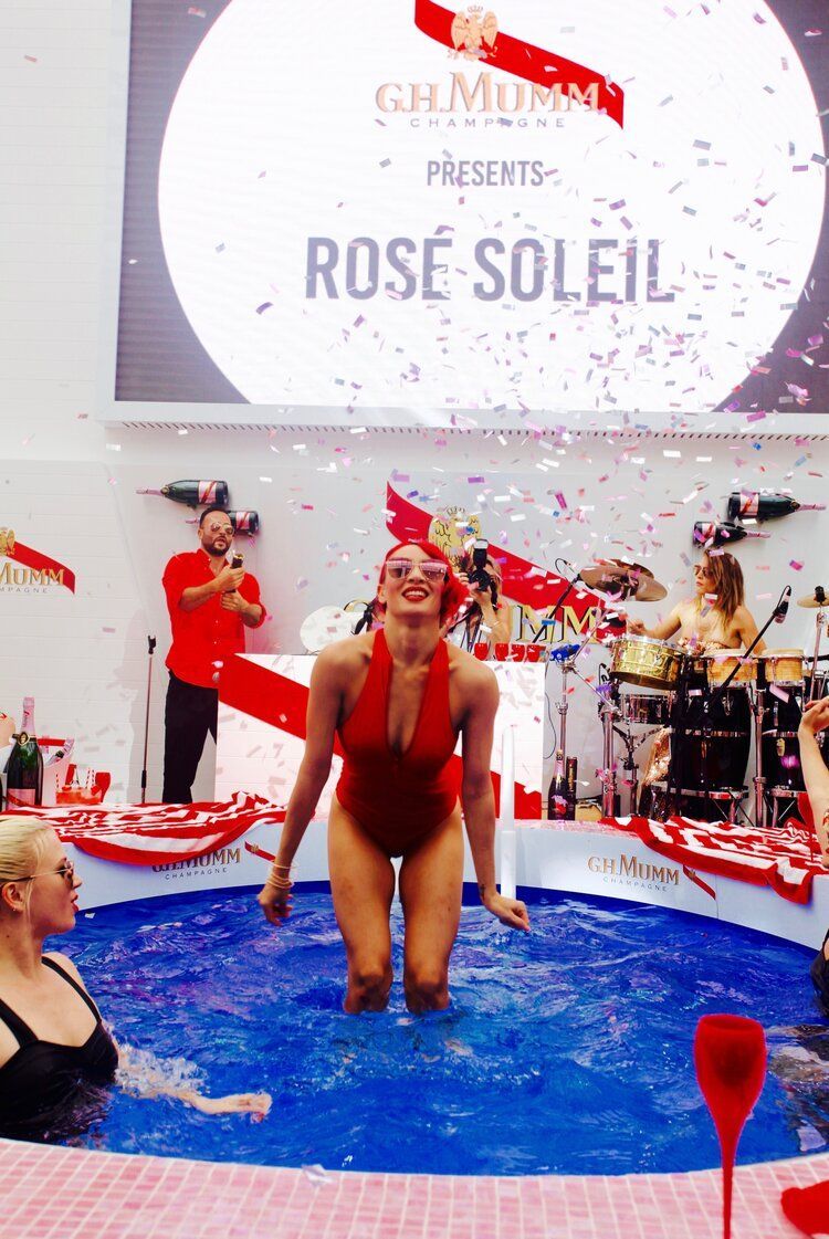 A woman in a red swimsuit is kneeling in a pool of water