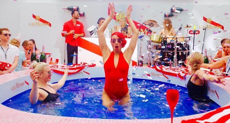 A woman in a red swimsuit is standing in a pool surrounded by people.