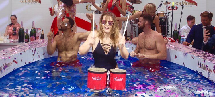 A group of people are playing drums in a pool.
