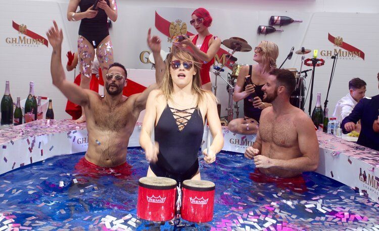 A woman in a swimsuit is playing drums in a pool of water.