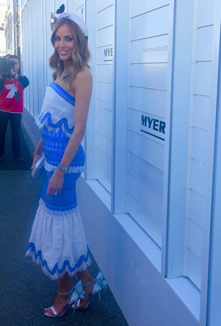 A woman in a blue and white dress is standing in front of a wall that says myer