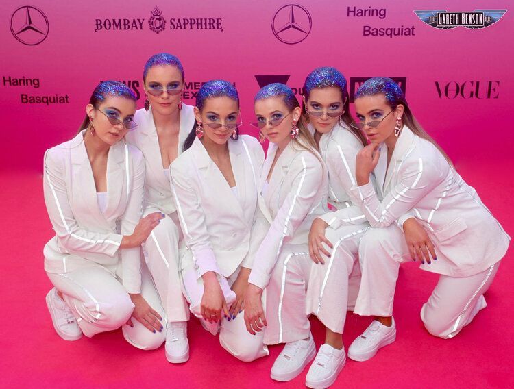 A group of women in white suits are posing for a picture
