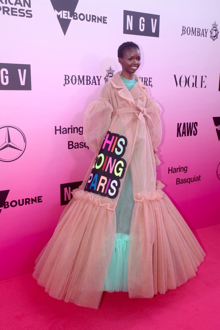 A woman in a long dress is standing on a pink carpet.