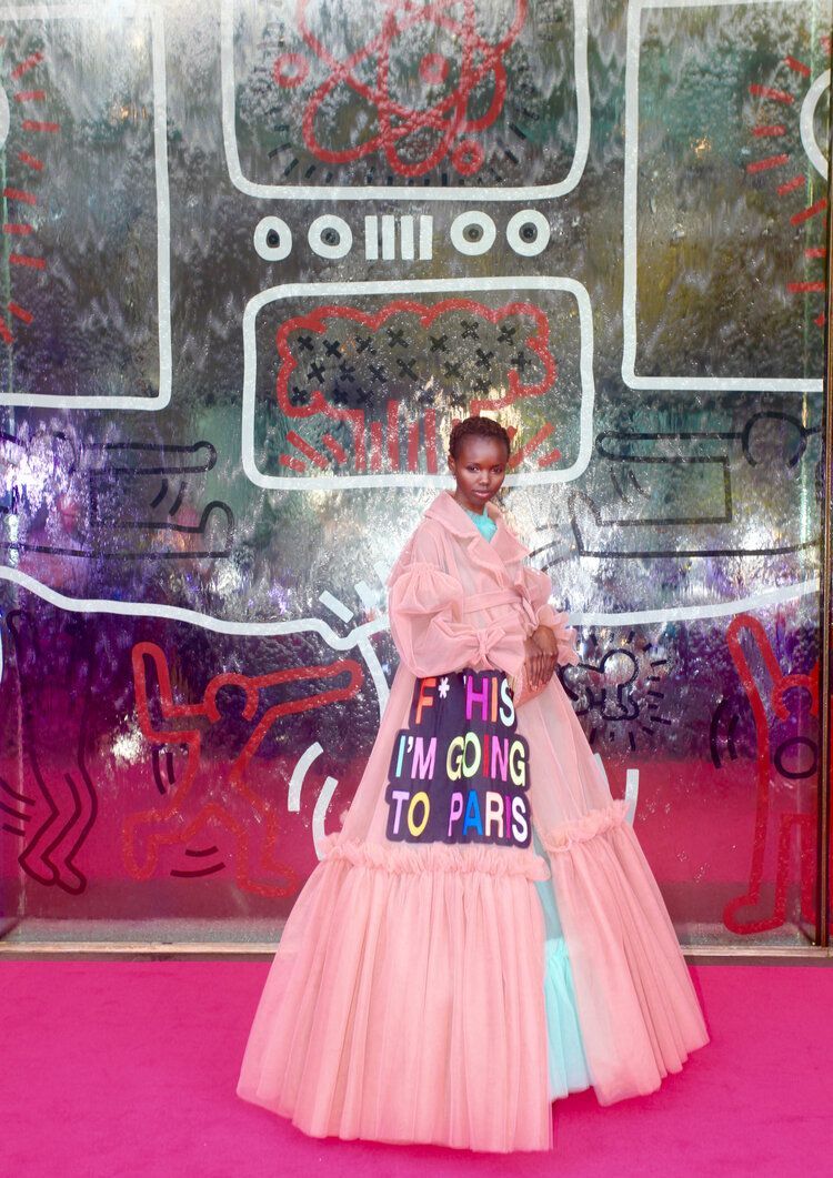 A woman in a pink dress is standing on a red carpet.
