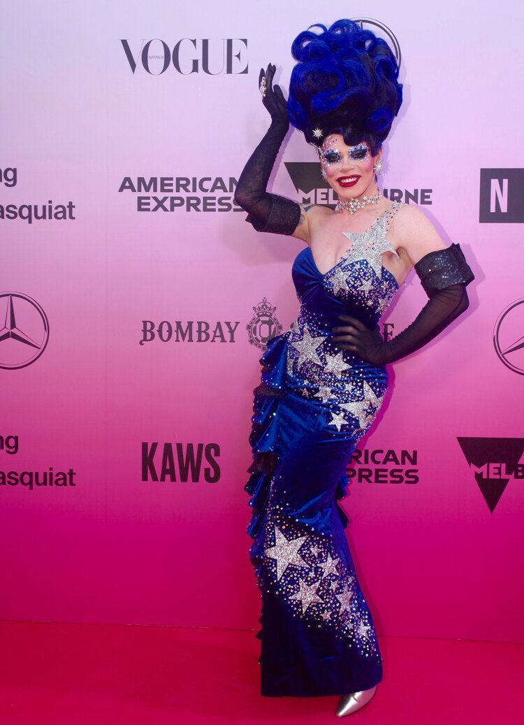A woman in a blue dress is standing on a pink carpet