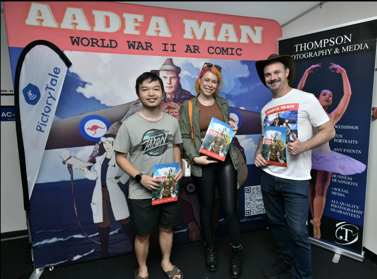 Three people standing in front of a sign that says aadea man