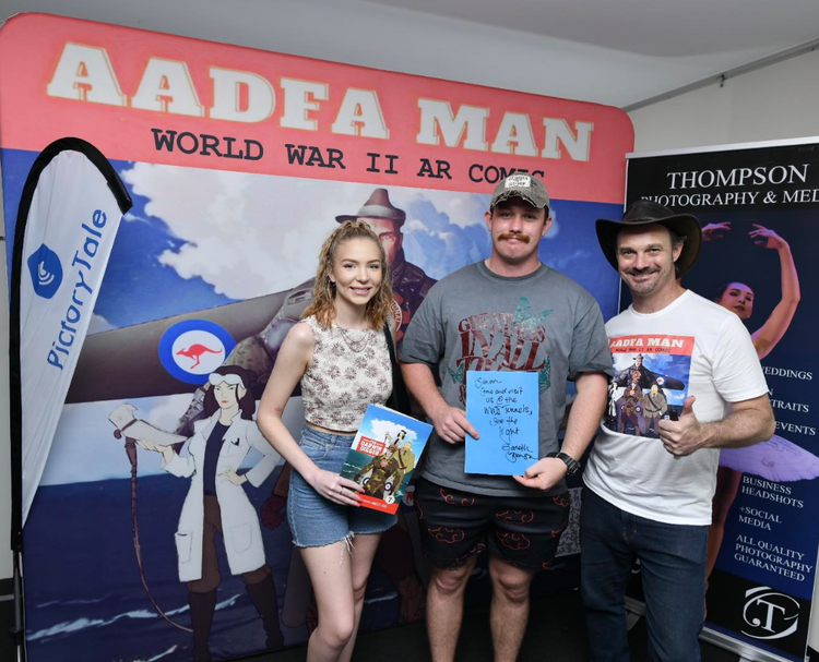 Three people standing in front of a sign that says aadea man