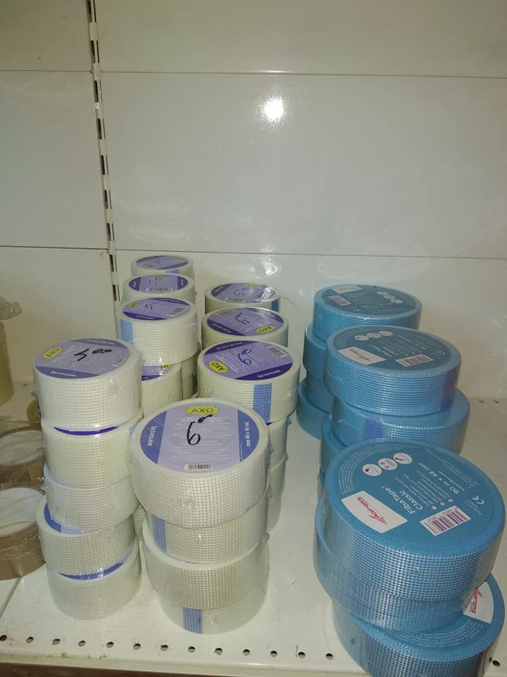 Scaffali con pile di rotoli di nastro adesivo bianco e blu con etichette.