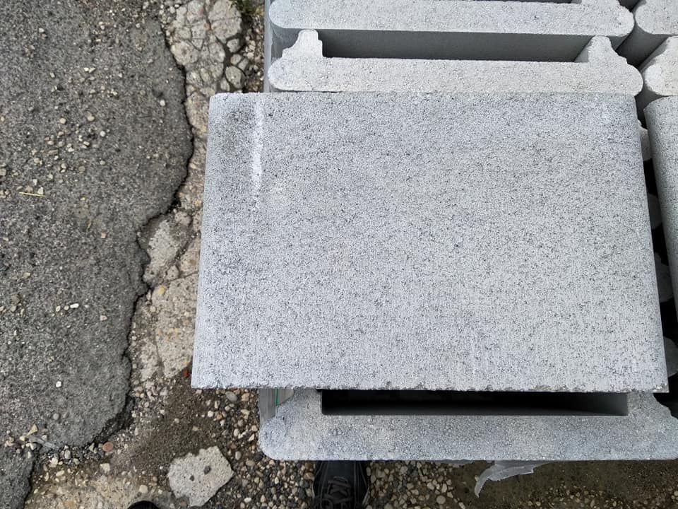 Blocchi di cemento grigio accatastati su una superficie ruvida.