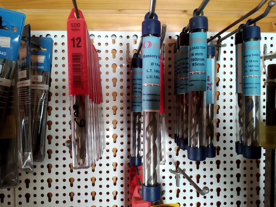 Punte da trapano appese a un pannello forato in tubi di plastica trasparente, di varie dimensioni.