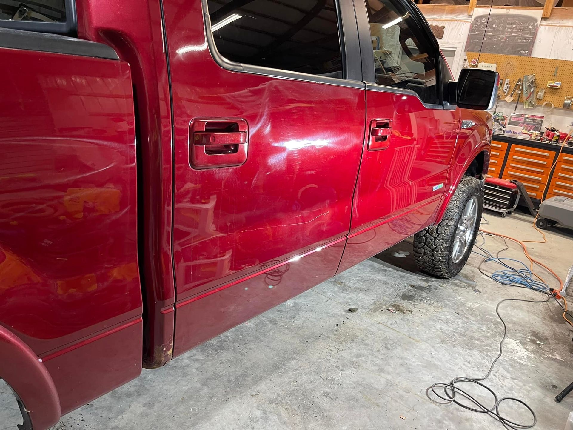 Red pickup truck with visible dents and scratches on the side door.