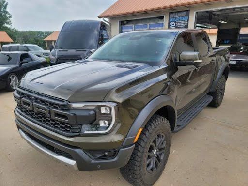 Dark green Ford Ranger Raptor pickup truck parked outside a building.