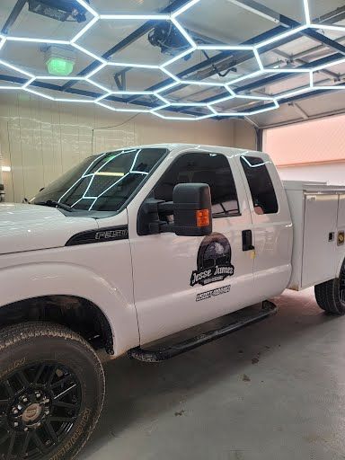 White Ford truck with tinted windows parked in a garage with hexagon-shaped lights on the ceiling.