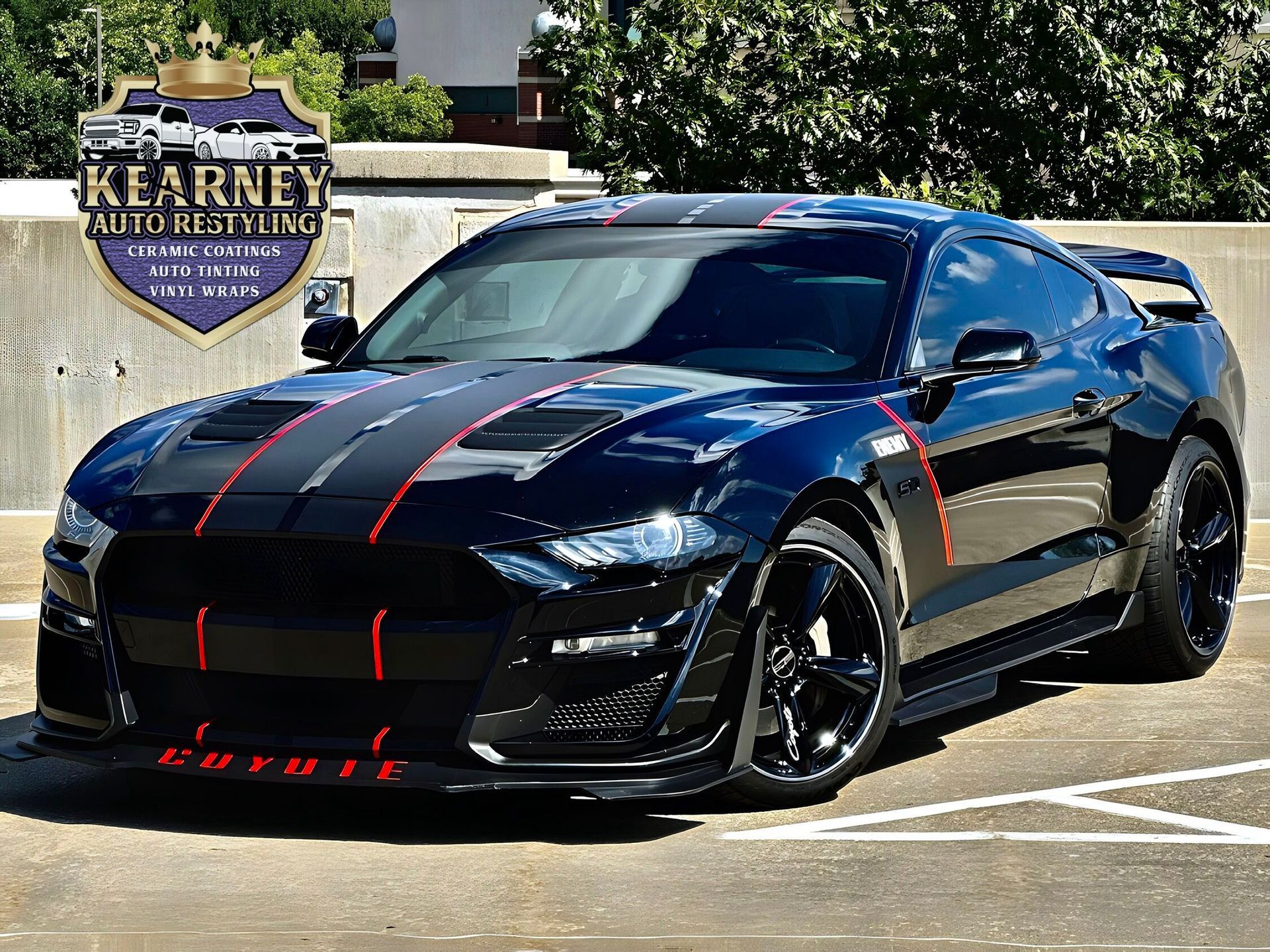 Black Ford Mustang with red stripes and accents, parked outdoors.