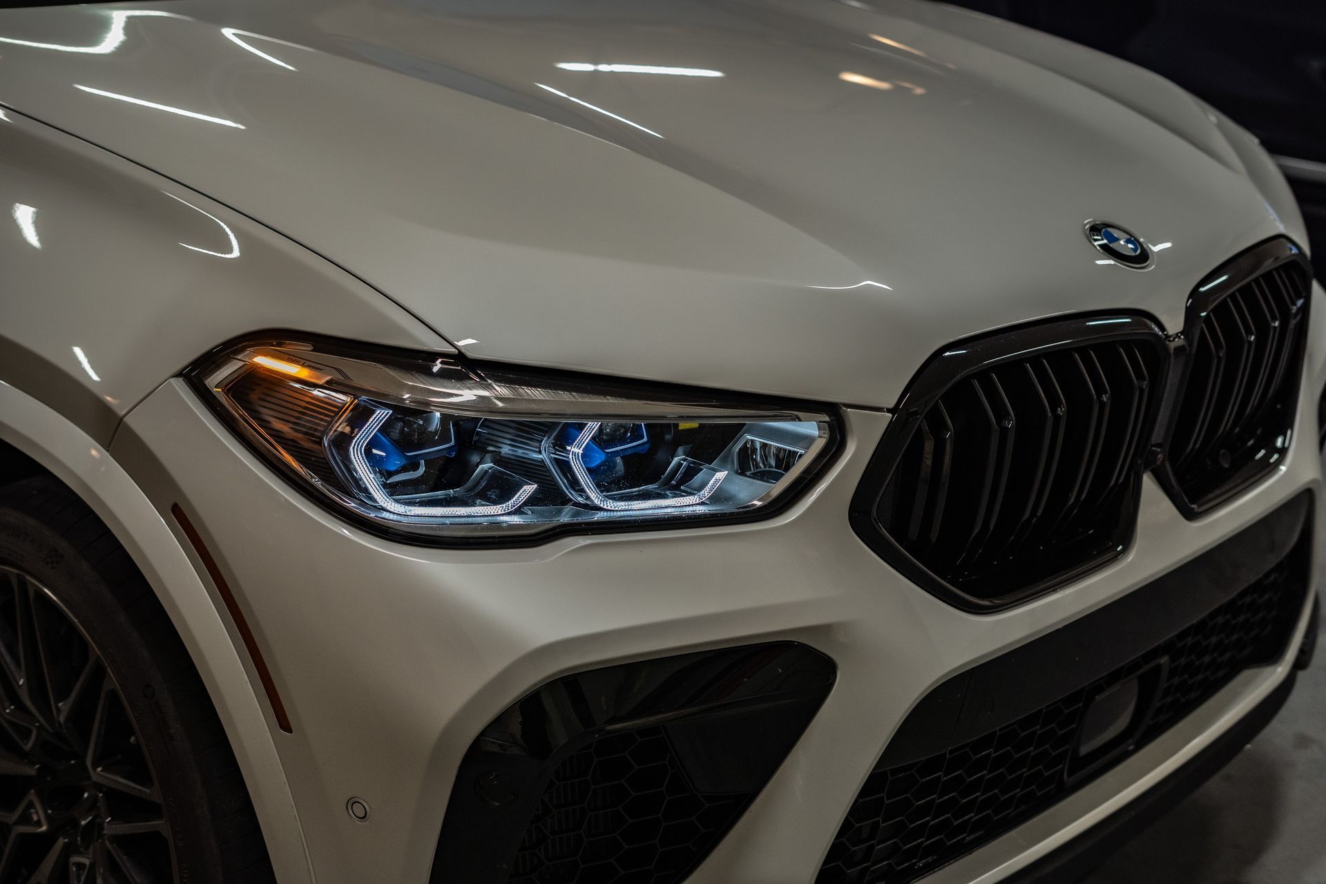 White BMW X6 with black grill and headlights illuminated.