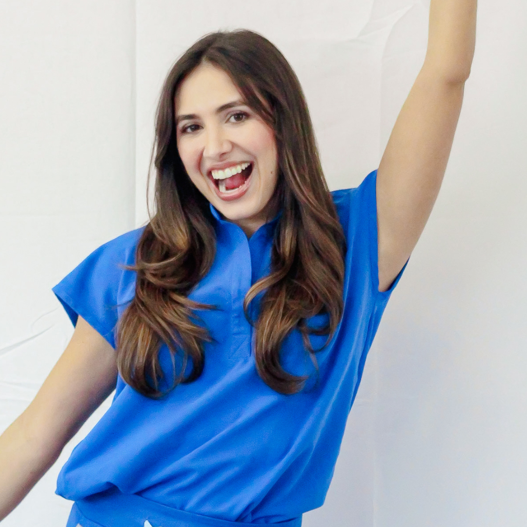 A woman in a blue shirt is raising her arm in the air.