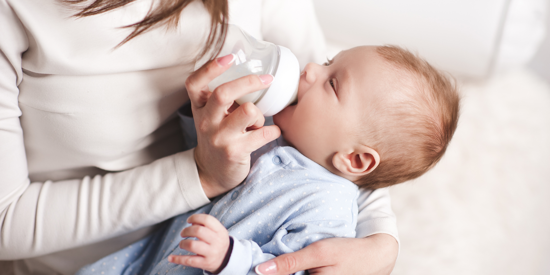 A woman is feeding her baby from a bottle.