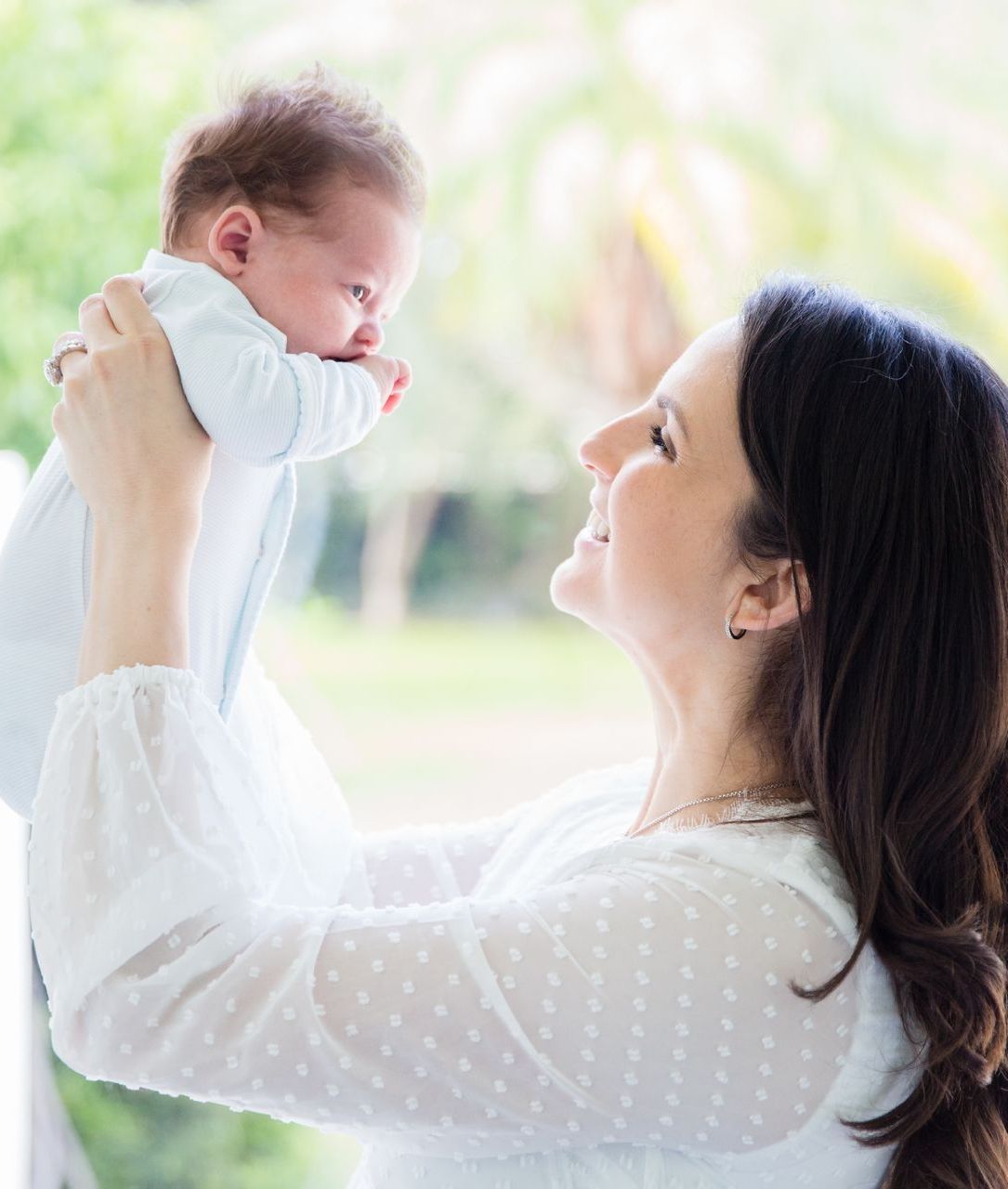 A woman is holding a baby up in the air