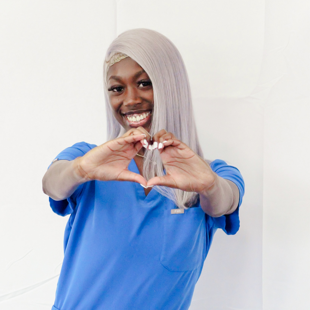 A woman in a blue shirt is making a heart shape with her hands