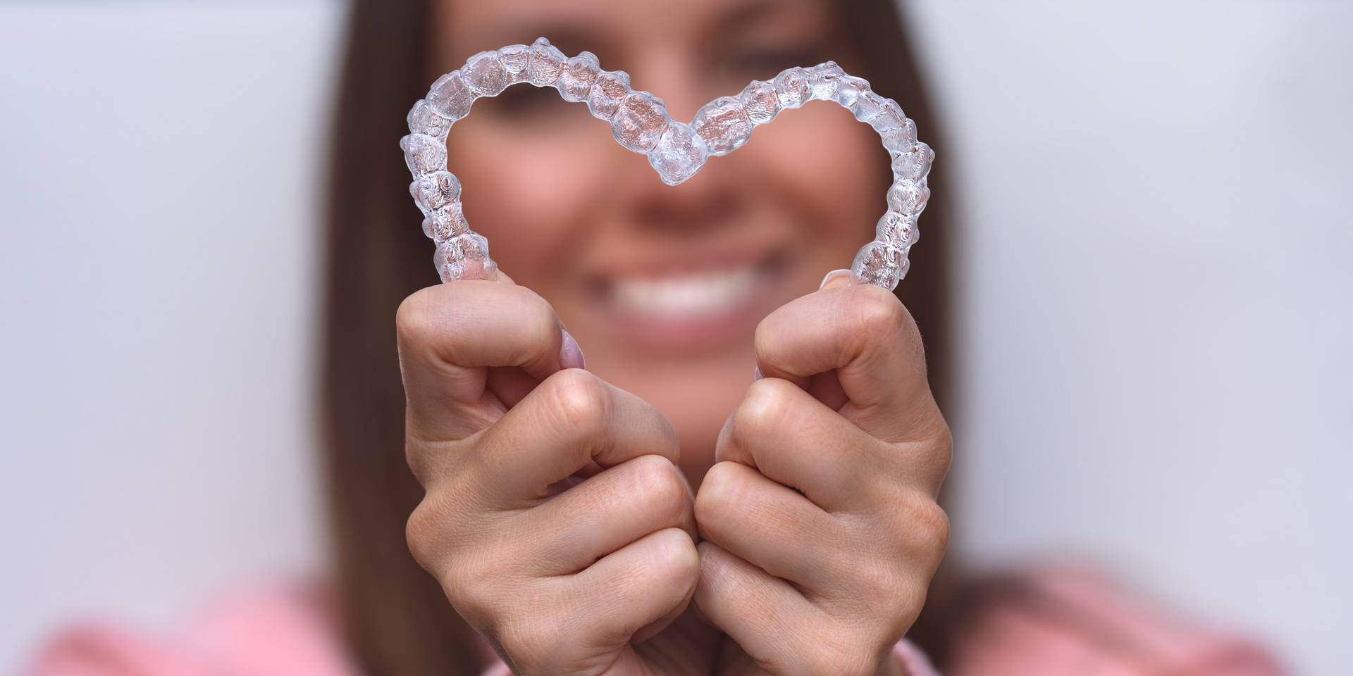 A woman is holding a heart shaped retainer in her hands.