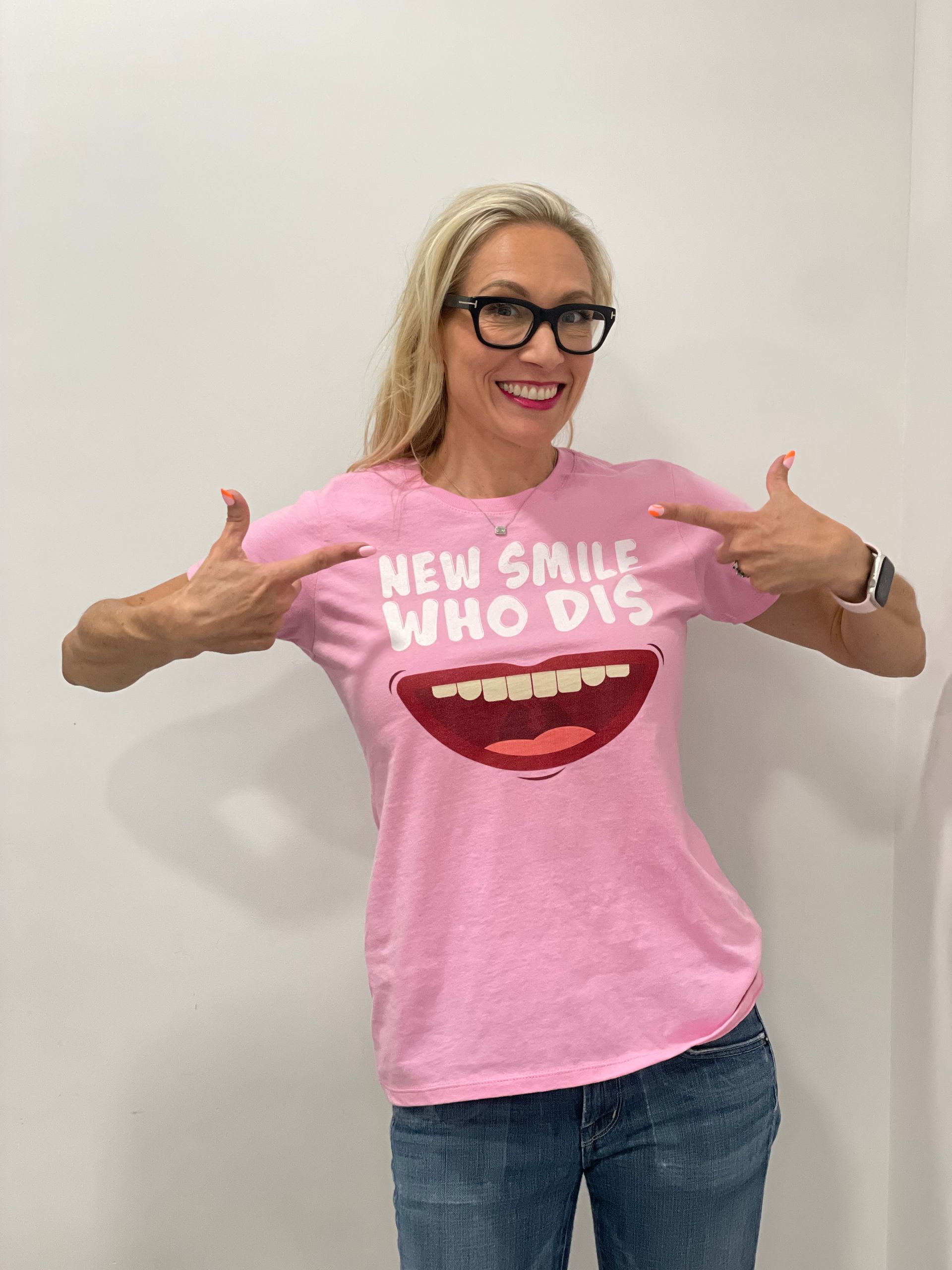 A woman wearing a pink shirt that says new smile who dis
