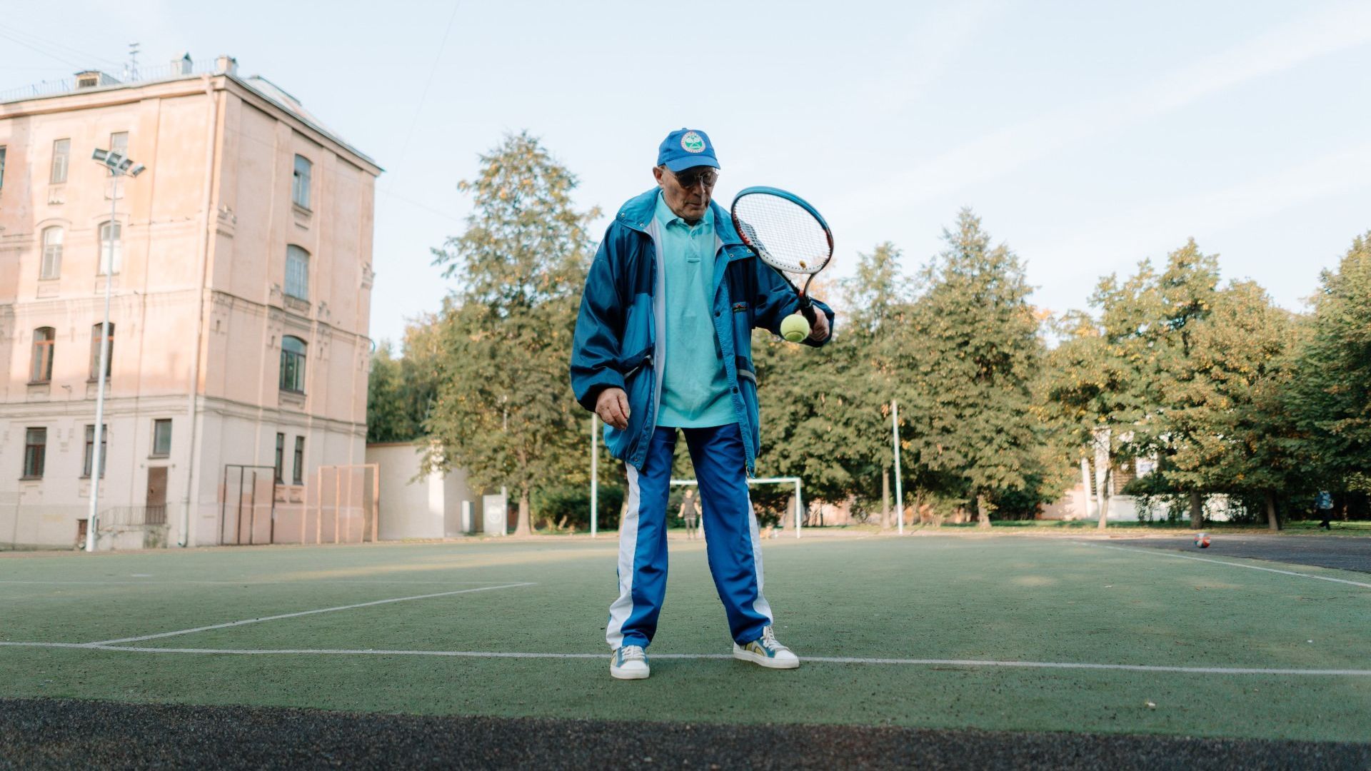 Old man holding Tennis Racket playing ball in the Park