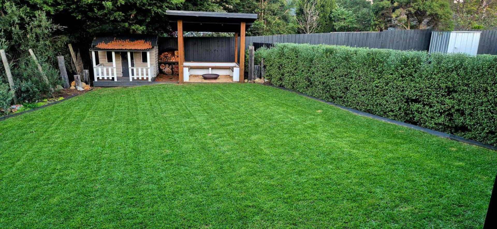 A large lush green lawn with a gazebo in the background.