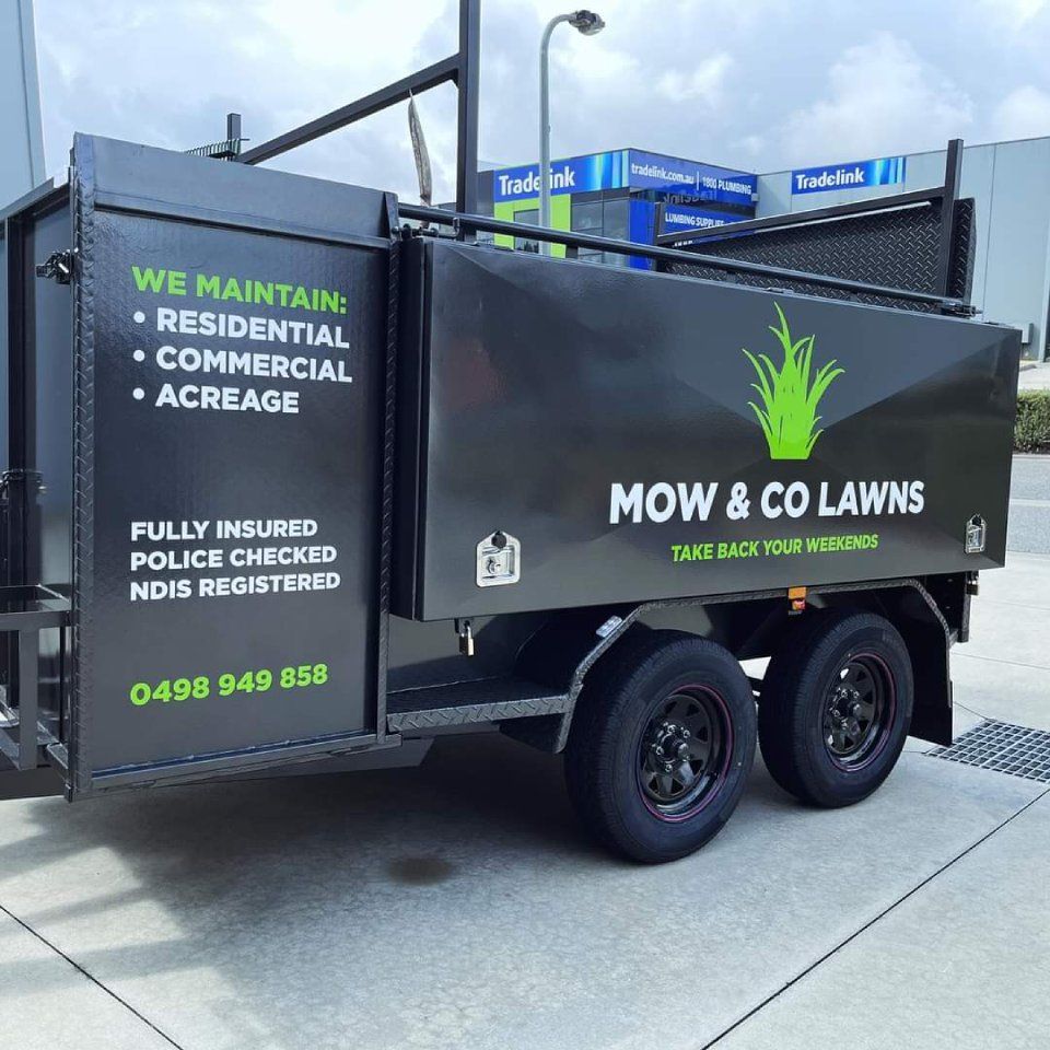 A mow and co lawns trailer is parked on the side of the road