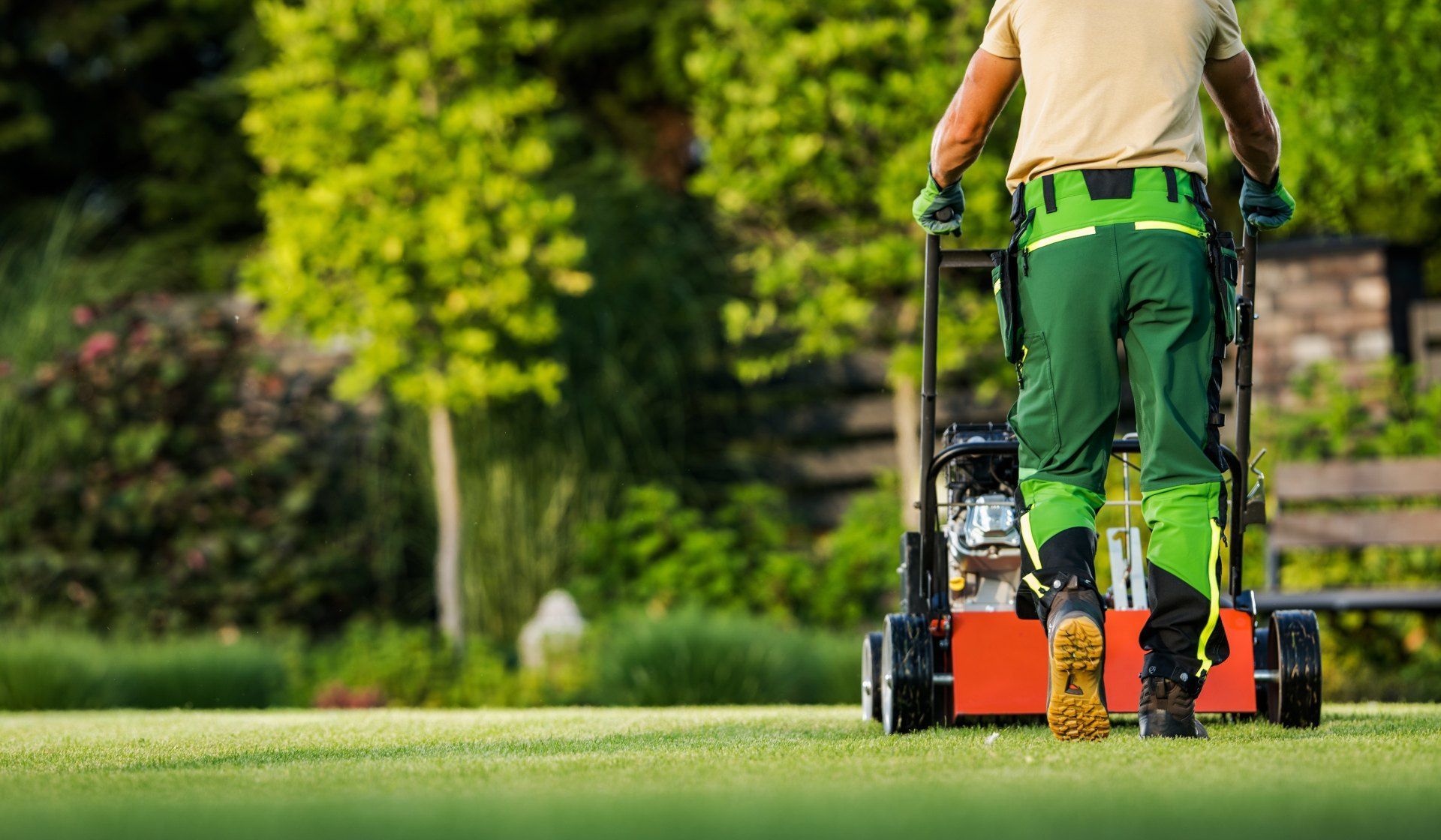A man is mowing a lush green lawn with a lawn mower.