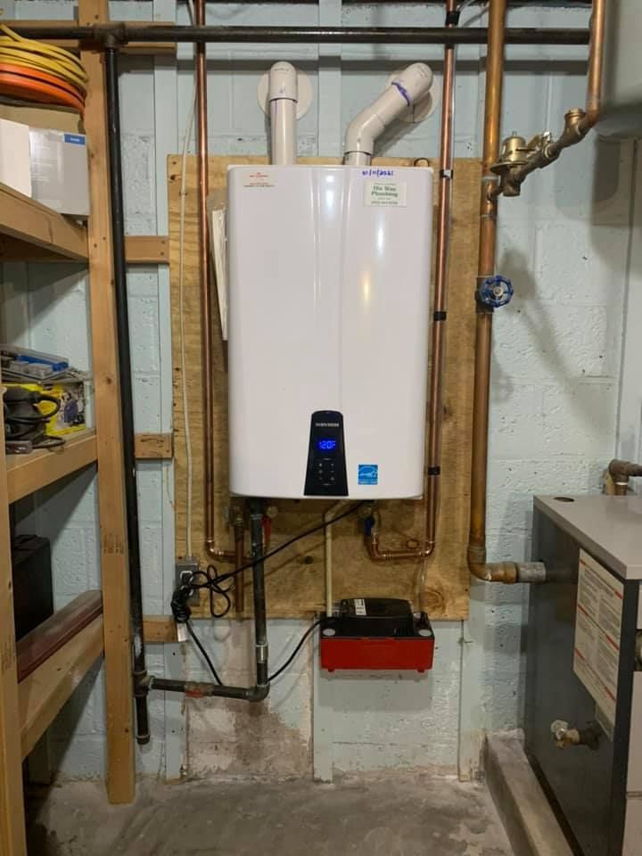 A white water heater is mounted to the wall in a basement.
