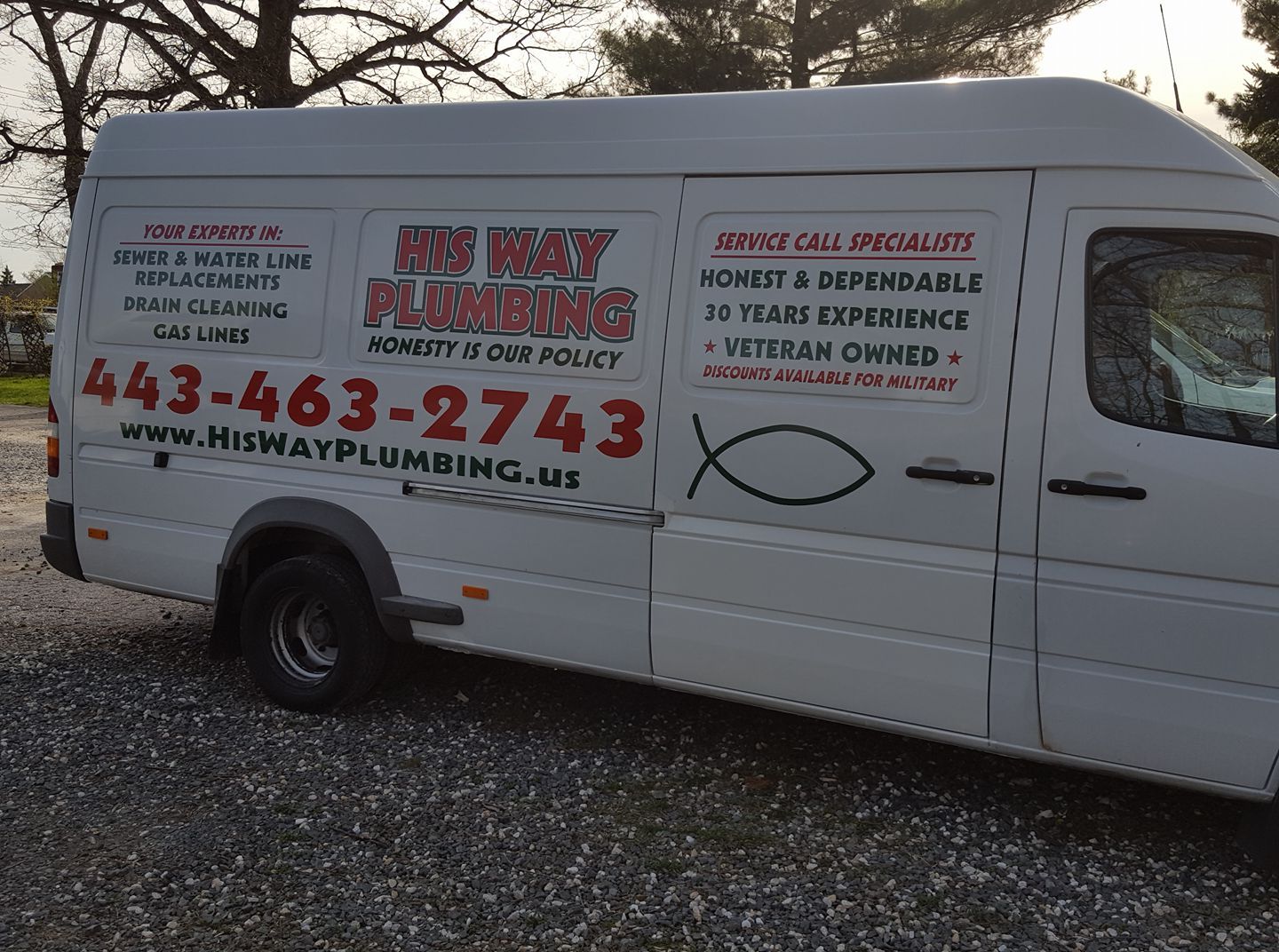 A white his way plumbing van is parked in a gravel lot