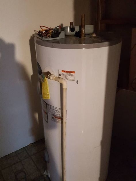 A white water heater is sitting in a room next to a wall.