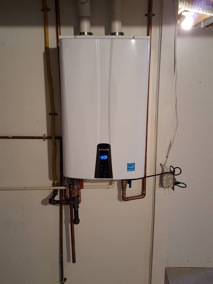 A white water heater is hanging on a white wall.
