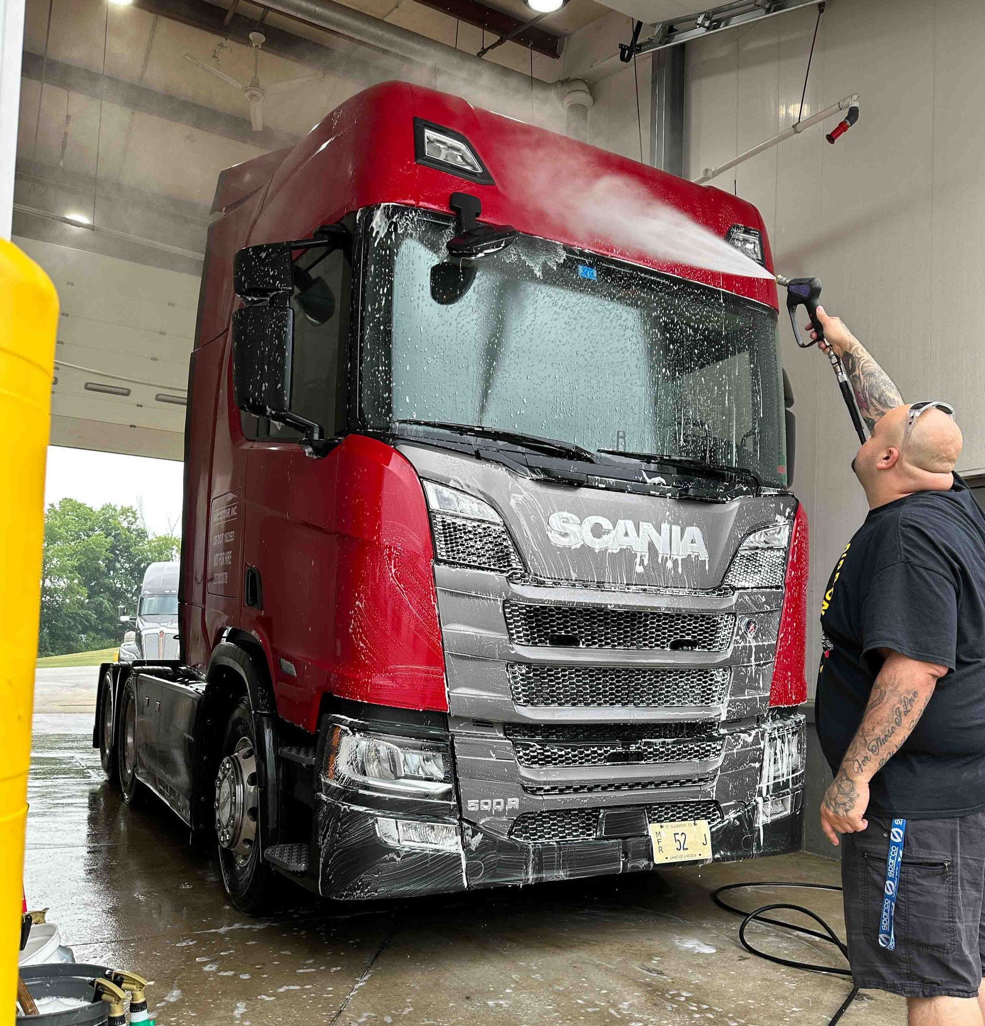 A person wearing black gloves is polishing the hood of a red car.