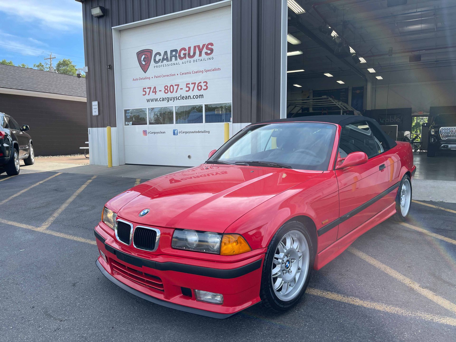 Red BMW convertible parked in front of a garage, 
