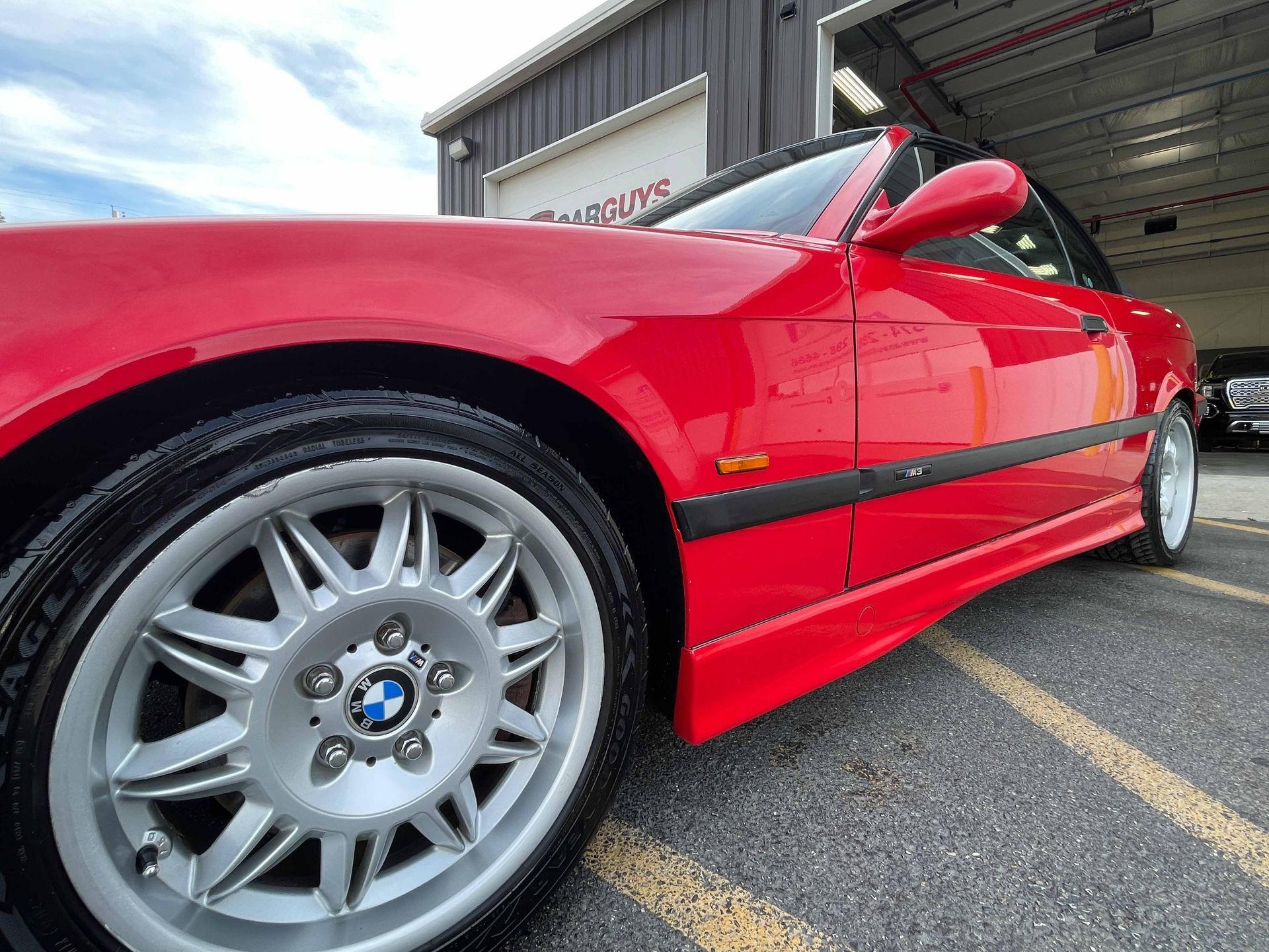 Red BMW convertible with silver wheels parked outside a building.