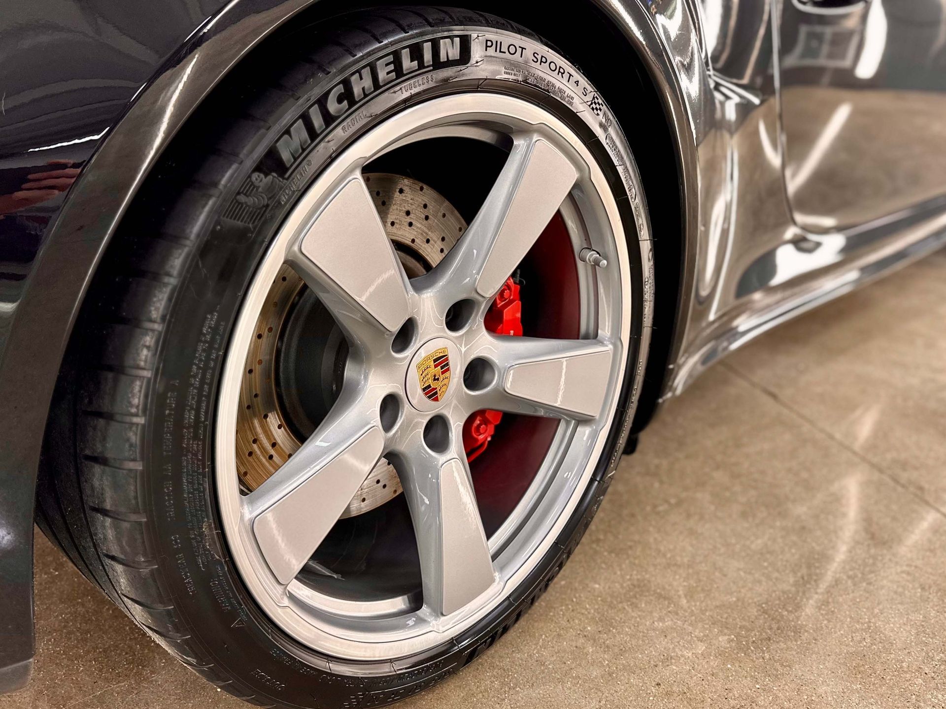 Close-up of a silver car wheel with a Michelin tire and red brake calipers.