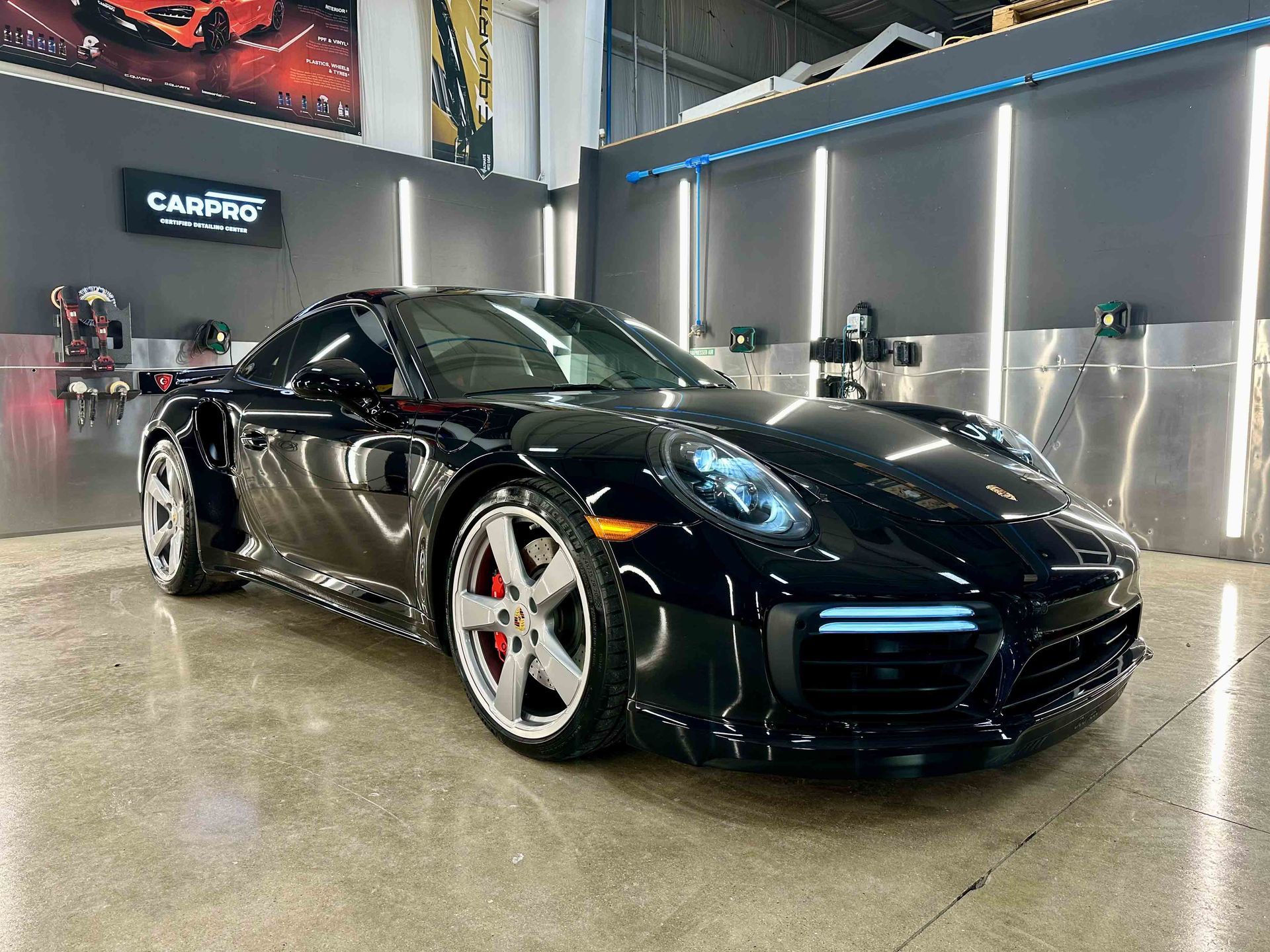 Black Porsche sports car inside a car detailing shop.