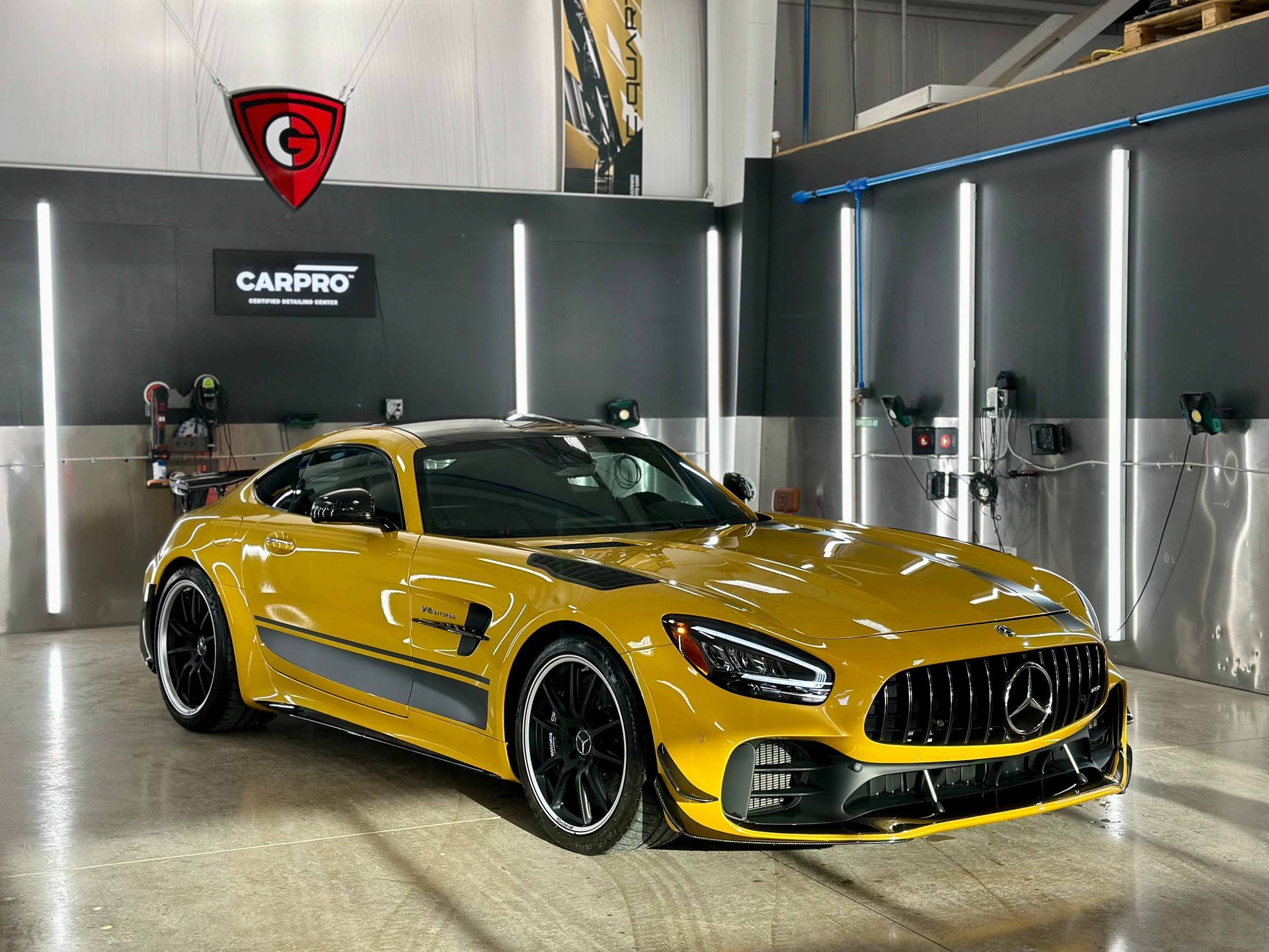 Yellow Mercedes AMG GT sports car parked in a garage with detailing equipment.
