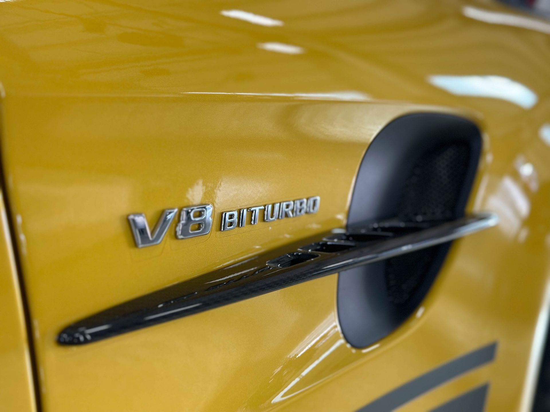 Yellow car with V8 BITURBO emblem and black vent.