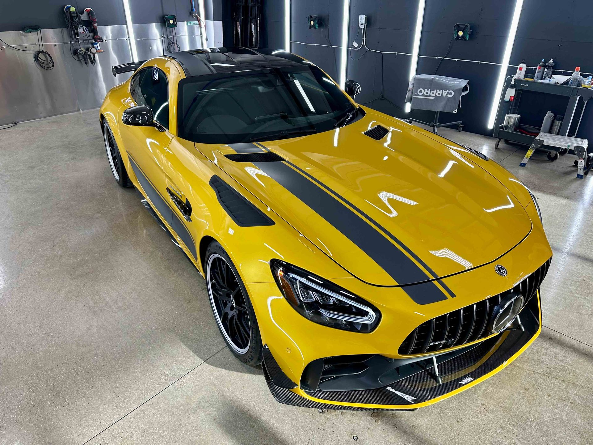 A person wearing black gloves is polishing the hood of a red car.